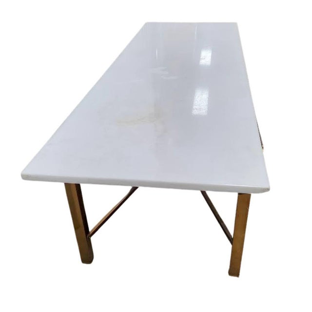 This is a beautiful vintage coffee table in the style of Paul McCobb. The base is square tubular brass, with a classical X...