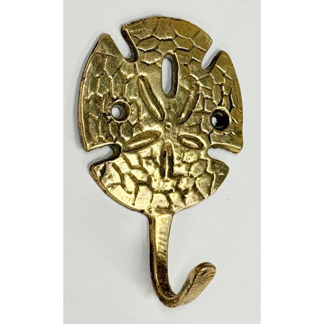Vintage solid brass hook with coastal sand dollar motif. Patina to brass.