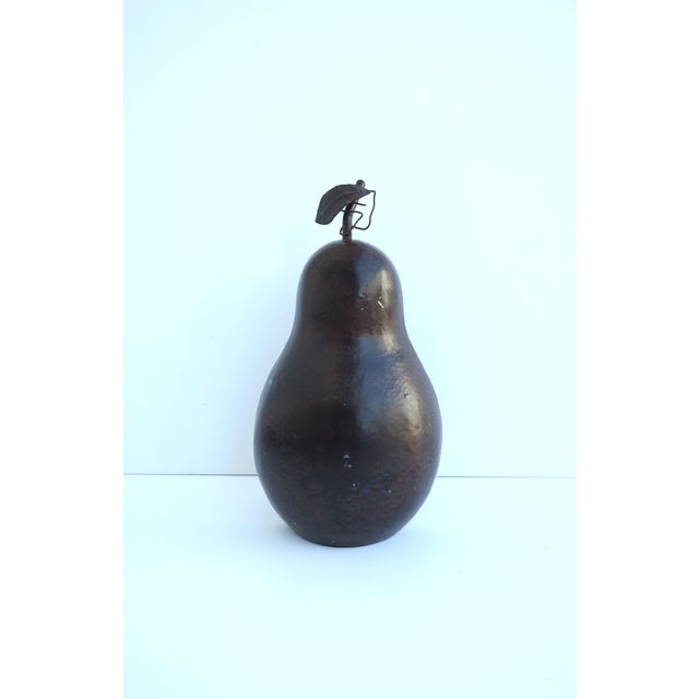 A cast iron pear fruit doorstop, (door stop, doorstopper), with a dark brown enamel surface and leaf detail, circa...