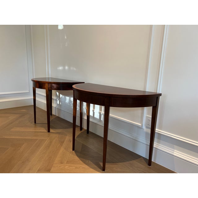 Hepplewhite style early twentieth century demi-lune tables in lovely condition. Beautiful wood with inlays and tapered legs.