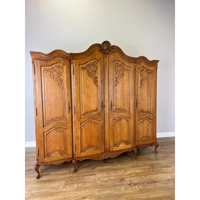 A beautifully detailed Vintage French Louis wardrobe in oak, featuring four panelled doors with elaborate carved...