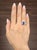 A captivating 4.25-carat oval-cut sapphire commands attention with its deep blue hue. Accentuated by two 1.00-carat oval-...