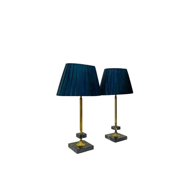 Refined pair of classical table lamps featuring slender fluted brass stems mounted on solid square bases in dark marble....