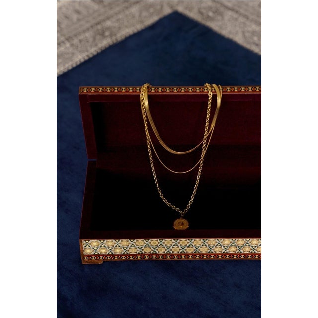 A wooden jewelry and keepsake box with a colorful floral composition on the lid, framed by geometric marquetry. The...