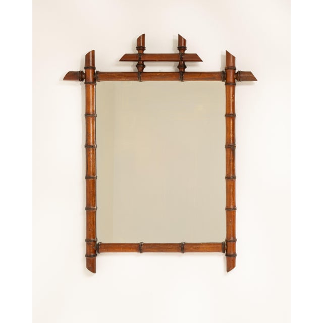 A decorative mirror featuring faux bamboo detailing, reflecting the period fascination with exotic motifs. The lightweight...