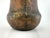Antique hand-hammered copper vessel with a substantial, rounded form and visible riveted seam detailing. The richly...