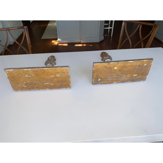 Pair of faux painted and gilded wooden wall brackets. Distressed whitewashed finish over natural wood giving aged...