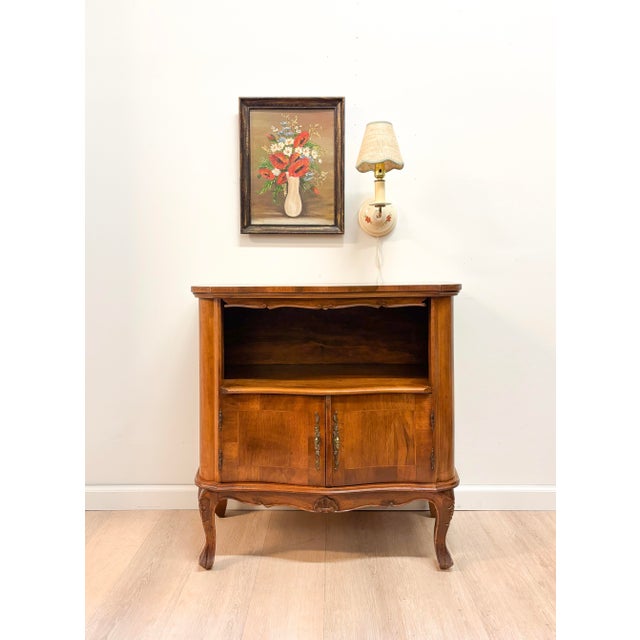 A charming French Provincial cabinet with soft, romantic lines and warm walnut tones. An open display shelf up top is...