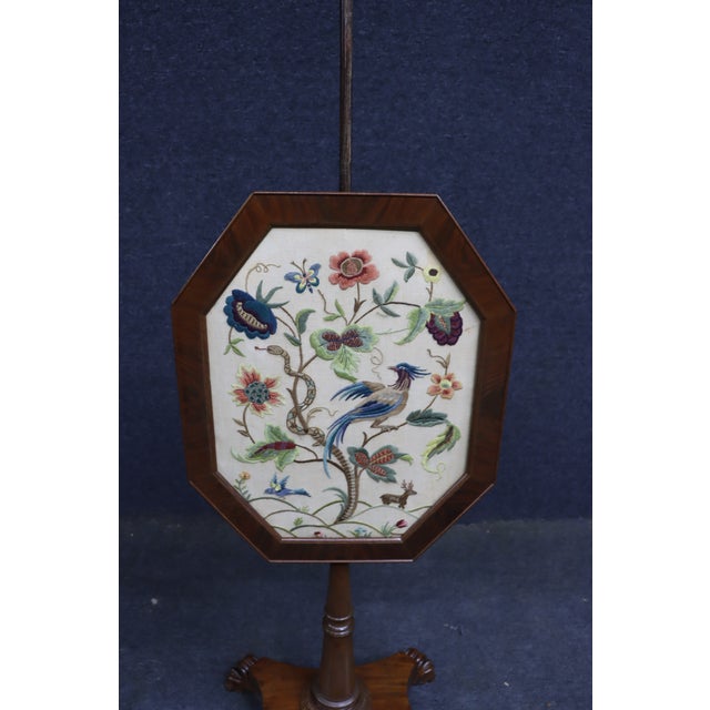 Empire-style firescreen featuring an octagonal mahogany-framed panel with embroidered crewelwork depicting an exotic bird,...