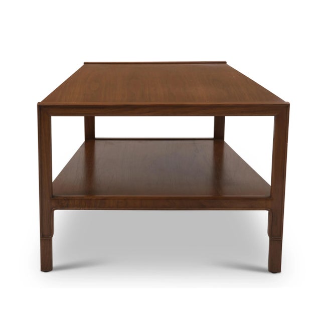 A John Stuart Janus Collection trapezoid table in walnut, 1960s. Unmarked. The front width is 20”, the back width is 28”....