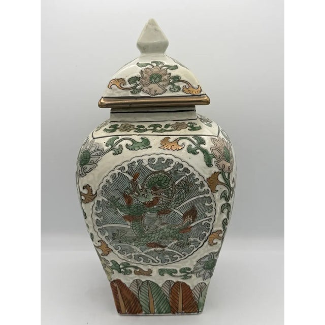 This Macau Famille Verte porcelain lidded ginger jar features a hand-painted dragon motif with detailed green, red, and...