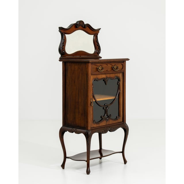 A tall, narrow Victorian cabinet designed for efficient storage within limited space. The simple proportions and...