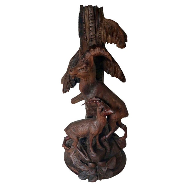 Beautifully detailed wooden carving depicting three deer gathered around a tree trunk, resting on a base decorated with...