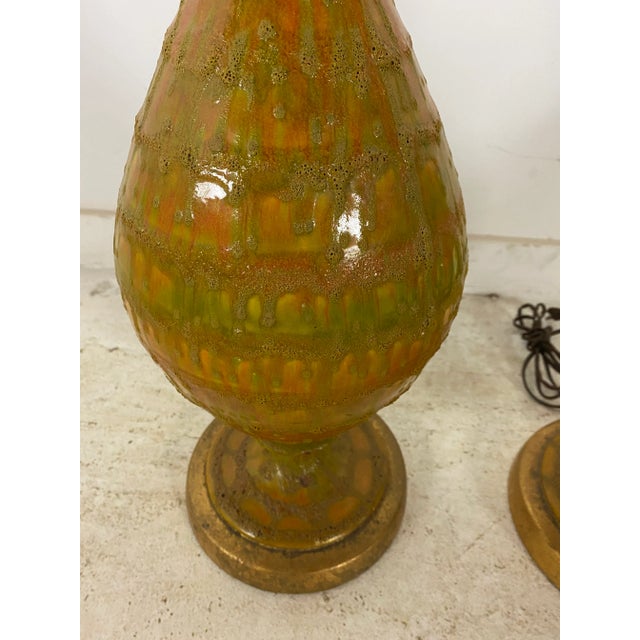 A pair of fantastic vintage MCM lava drip glaze lamps in orange and green. Includes harp and finials. Gold colored base...