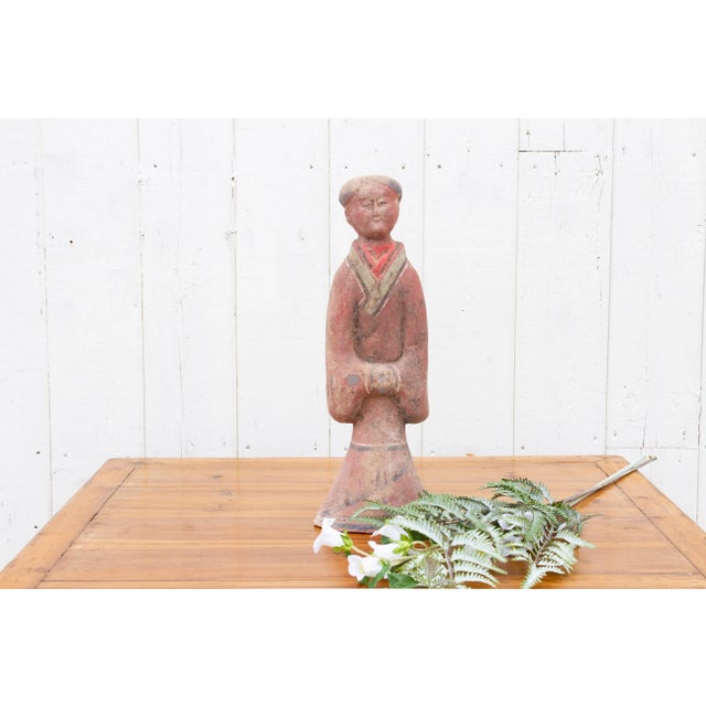 This tall Chinese painted pottery figure of a female courtier embodies the elegance of the Han Dynasty. Crafted in the...
