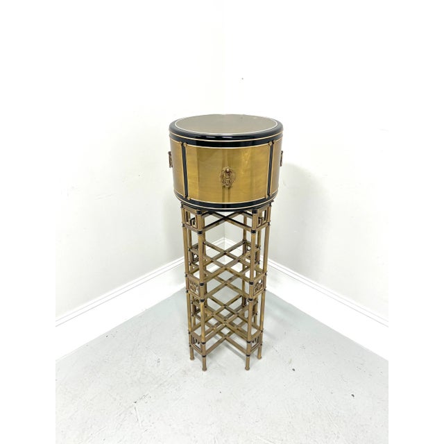 An Asian style plant stand, unbranded. Solid wood core to drum-shaped upper portion with plated brass & black enamel,...