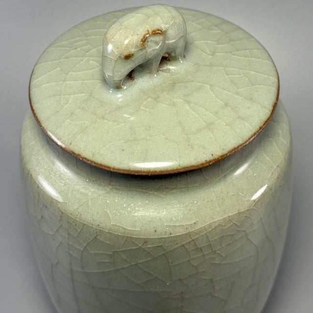 This elegant Chinese celadon covered jar is fitted with a lid and covered with fine crackle glaze. Crafted in the time-...
