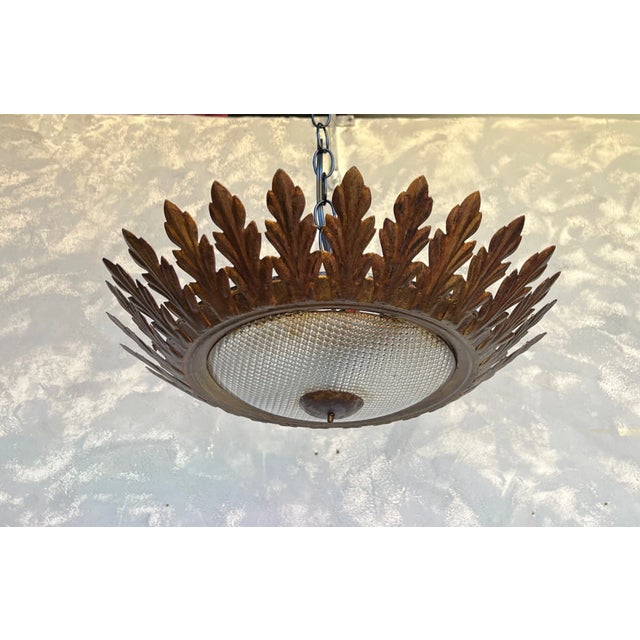 A simple but elegant Spanish flush mount ceiling fixture with a convex textured glass globe framed in evenly spaced leaves...