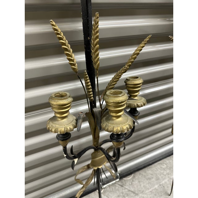 Black painted metal sword wall sconces for candles. Gold painted metal accompany the design and the candle cups are gold...