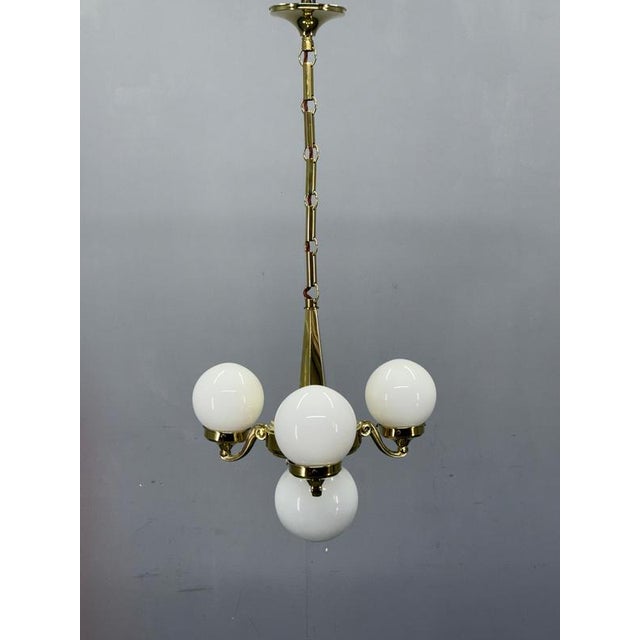 Original 1930s Art Deco chandelier from Czechoslovakia executed in solid brass with four opaline glass globes. The design...