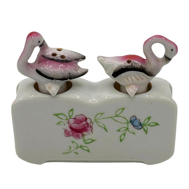 Mid-century pink and green ceramic flamingo tabletop salt & pepper with a holding base by Express. The set features two...