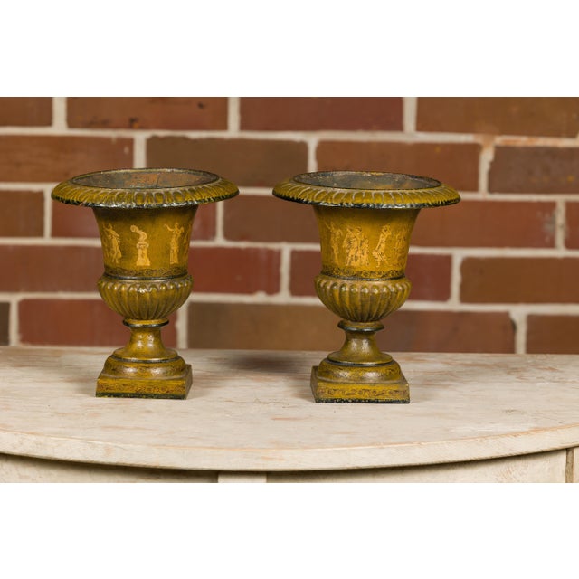 A pair of Neoclassical style iron urn planters from circa 1900 with liners and mythological figures. This pair of...