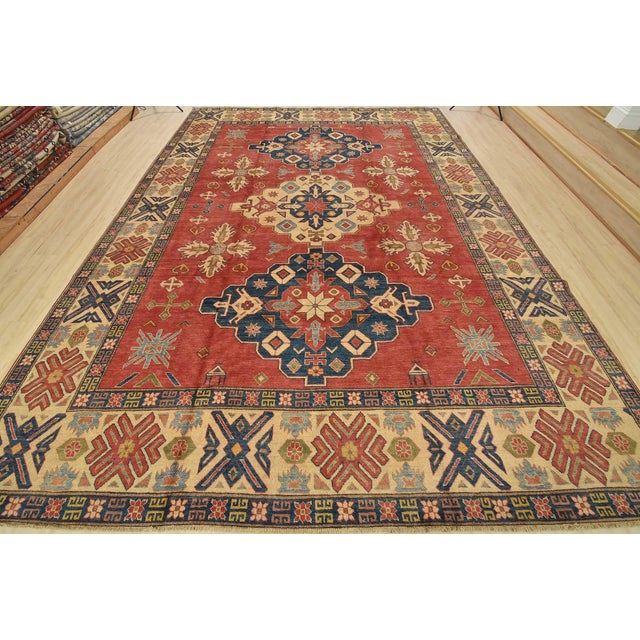 A tribal Caucasian Kazak rug hand-knotted with fine wool on a cotton foundation. This area rug features geometric...