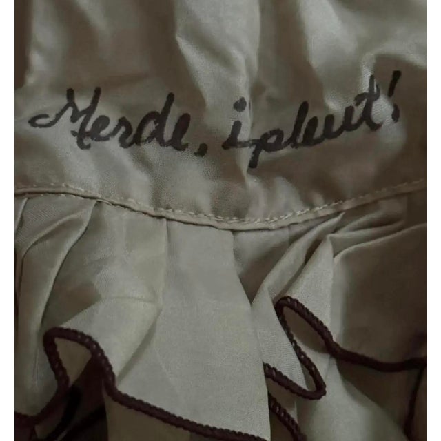 "Merde, il pleut!" — "Shit, it's raining!" A 1940s French umbrella with a ruffled edge, featuring the expressive...