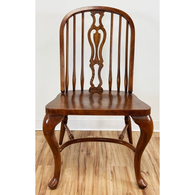 Timeless set of eight (8) vintage Windsor style dining chairs made of hard wood. Feature turned legs with stretchers, bow-...