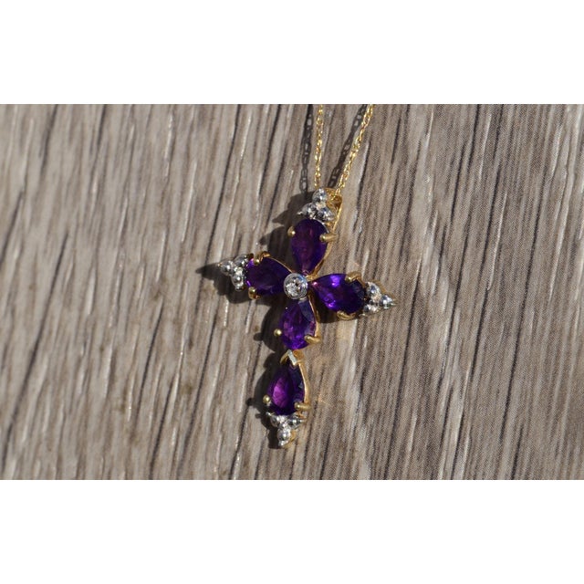Ladies Amethyst and Diamond Cross Necklace in Yellow Gold. Crafted in trendy yellow gold, this ladies necklace features a...