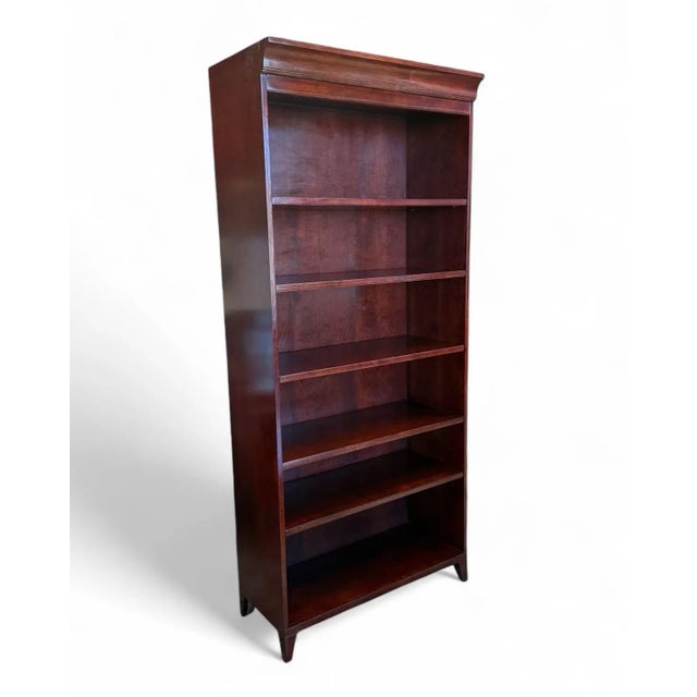 Tall bookcase by Sligh Furniture. The bookcase has small, tapered front feet and crown moulding. There are 4 adjustable...