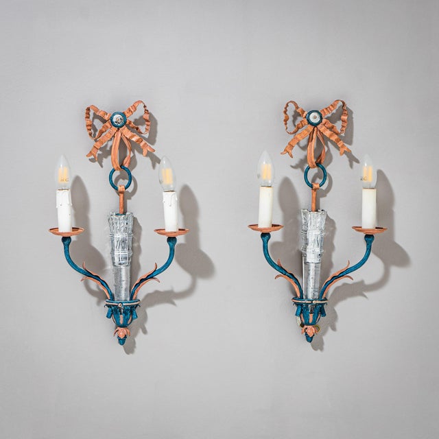 Pair of wall sconces in blue and pink tones with an antiqued charm, each featuring two candle arms, decorative glass...