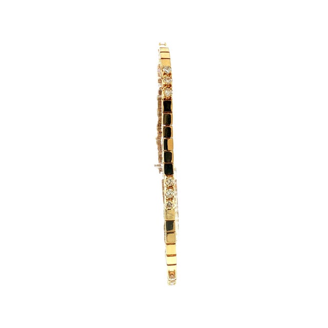 This late 20th-century bracelet features a 14k gold design with a sleek, modern aesthetic. The bracelet is adorned with 18...