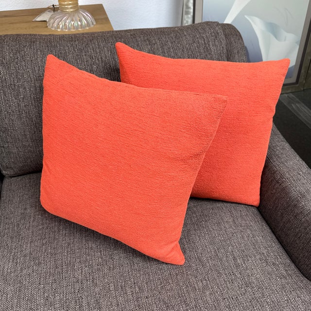 Design Plus Gallery presents a Pair of Woven Throw Pillows in Coral. These pillows feature a warm, vibrant pinkish-orange...