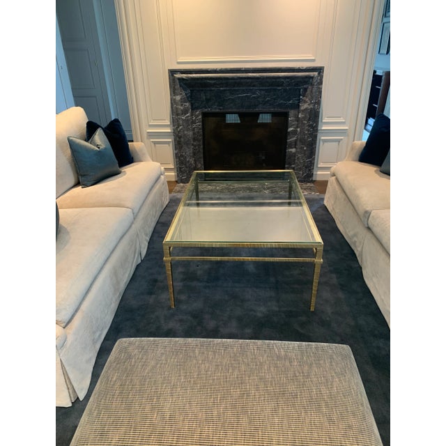 Sleek rectangular coffee table featuring an unlacquered satin brass frame with a warm gold finish and a 1/2" thick clear...