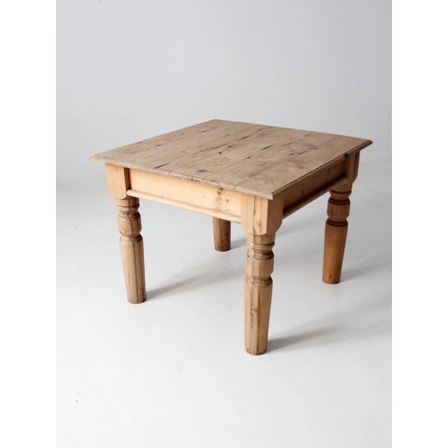 This is an antique wooden side table. The sturdy and versatile square table features thick turned legs. The natural wood...
