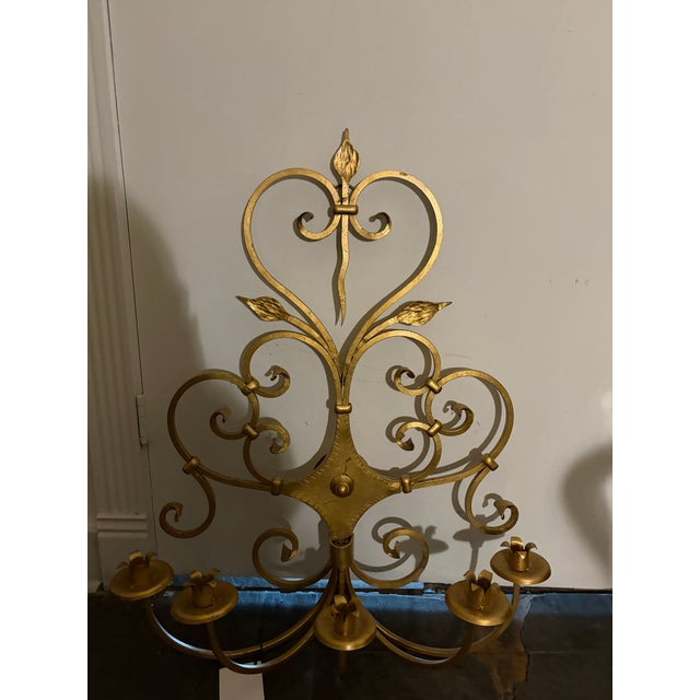 An exceptional pair of monumental gilt iron wall candelabras with elegant scrolling ironwork, stylized tulip details, and...
