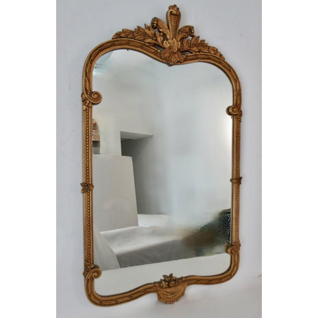 Vintage: C. 1960's; Gold gilded French Rococo-style, meets Hollywood Regency era wall mirror. It has a, prominent, foliate...