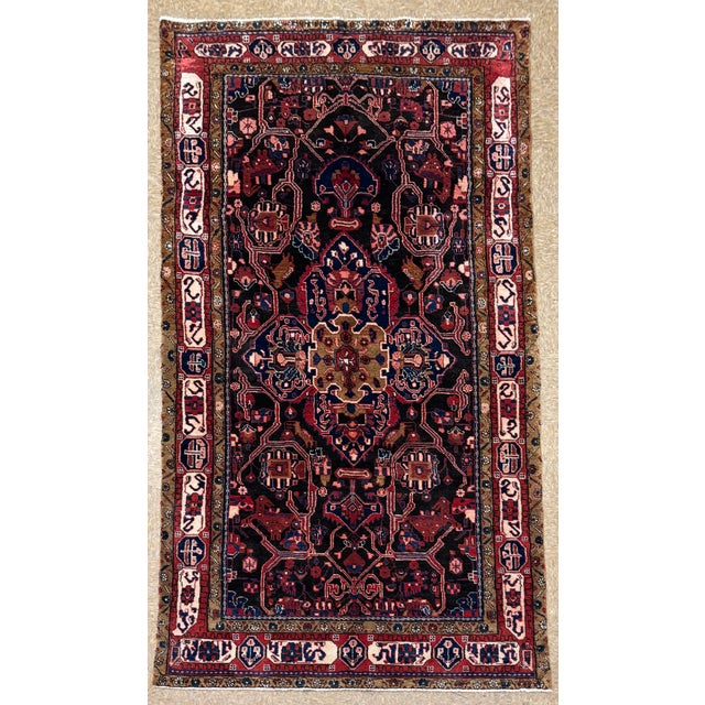 Antique hand-knotted rug from the Nahavand region of western Iran, featuring a central geometric medallion on a deep navy...