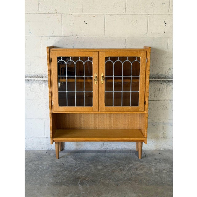 This bookcase features an enclosed upper section above an open lower shelf. Scalloped side panels and tapered legs create...