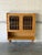 This bookcase features an enclosed upper section above an open lower shelf. Scalloped side panels and tapered legs create...