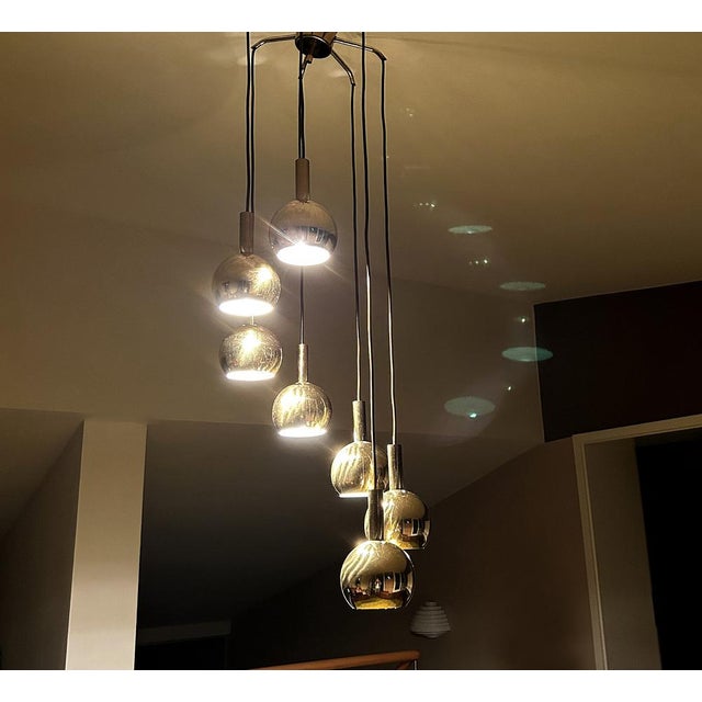 Mid century vintage pendant light, featuring 7 brass spheres with louvered top, arranged in a circular cascade alike array...