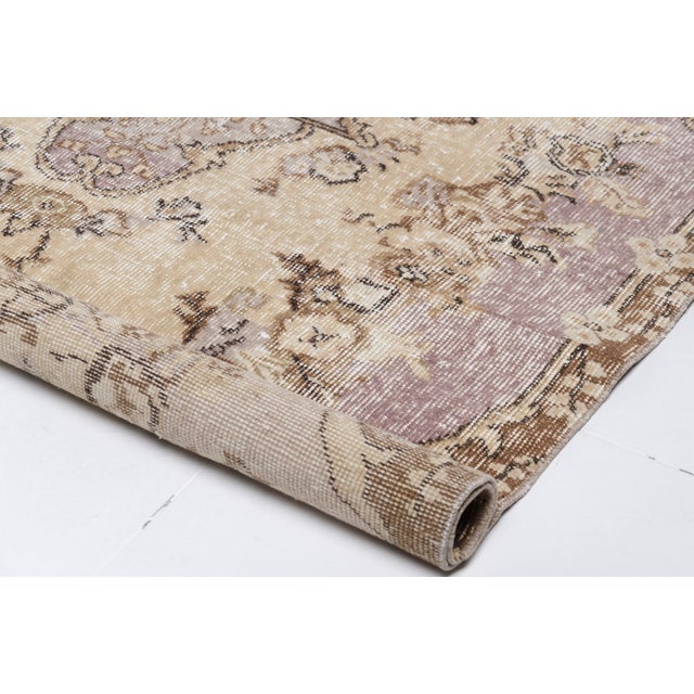 This is a vintage Turkish Oushak rug from the Mid 20th Century. The piece was hand-knotted.