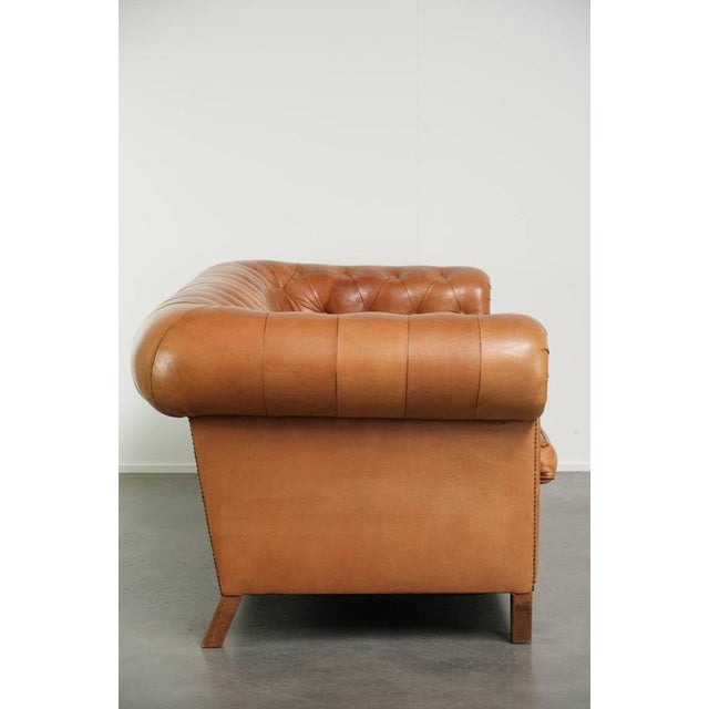 This unique 2.5-seater Chesterfield sofa, made of sheepskin and in excellent condition, features a beautiful light cognac...