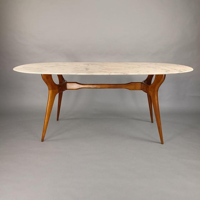 Elegant table from the 1950s. Beech wood frame with an oval marble top featuring gray veining and light pink highlights....
