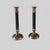 A pair of vintage candlesticks featuring slender black fluted columns with warm brass-toned mounts and broad circular...