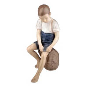 Mid-20th Century Scandinavian Modern Glazed Porcelain Sculpture of a Boy Sitting on a Rock by Danish Company Bing & Grøndahl