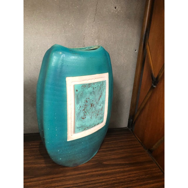 Ceramic vase with a 90’a sensibility . The blue portion layered on the white paint part of the the piece is metal. It is...