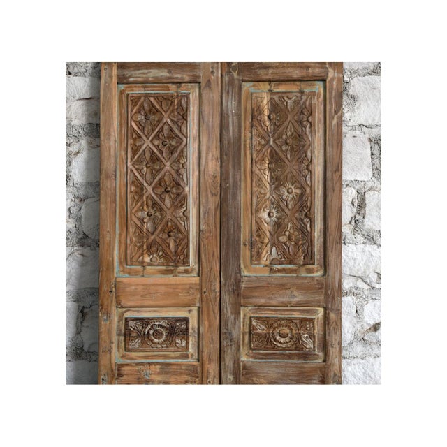 A stunning pair of antique double doors featuring intricate hand-carved floral motifs and a softly weathered whitewashed...