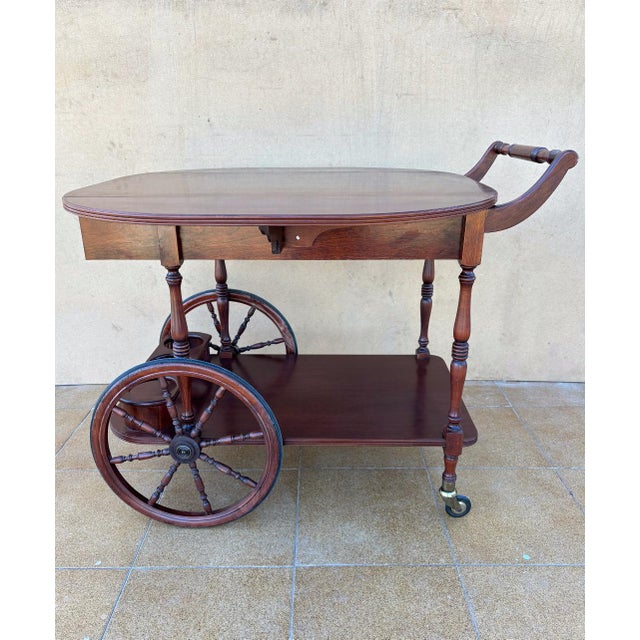 Charming mid-century bar cart crafted in rich wood, showcasing a warm tone and beautifully preserved grain. This elegant...